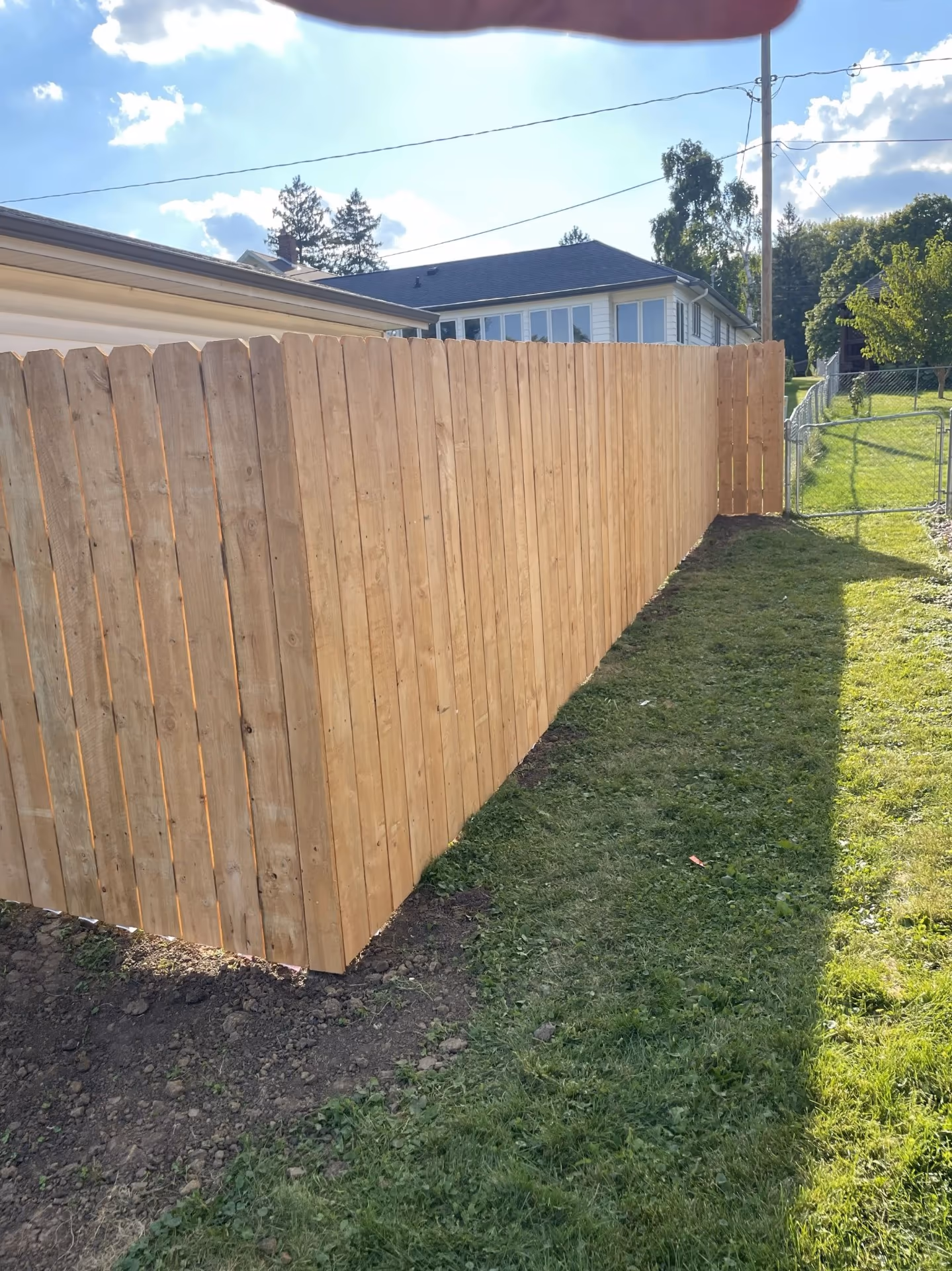 Completed wood privacy fence alongside garage with freshly graded soil