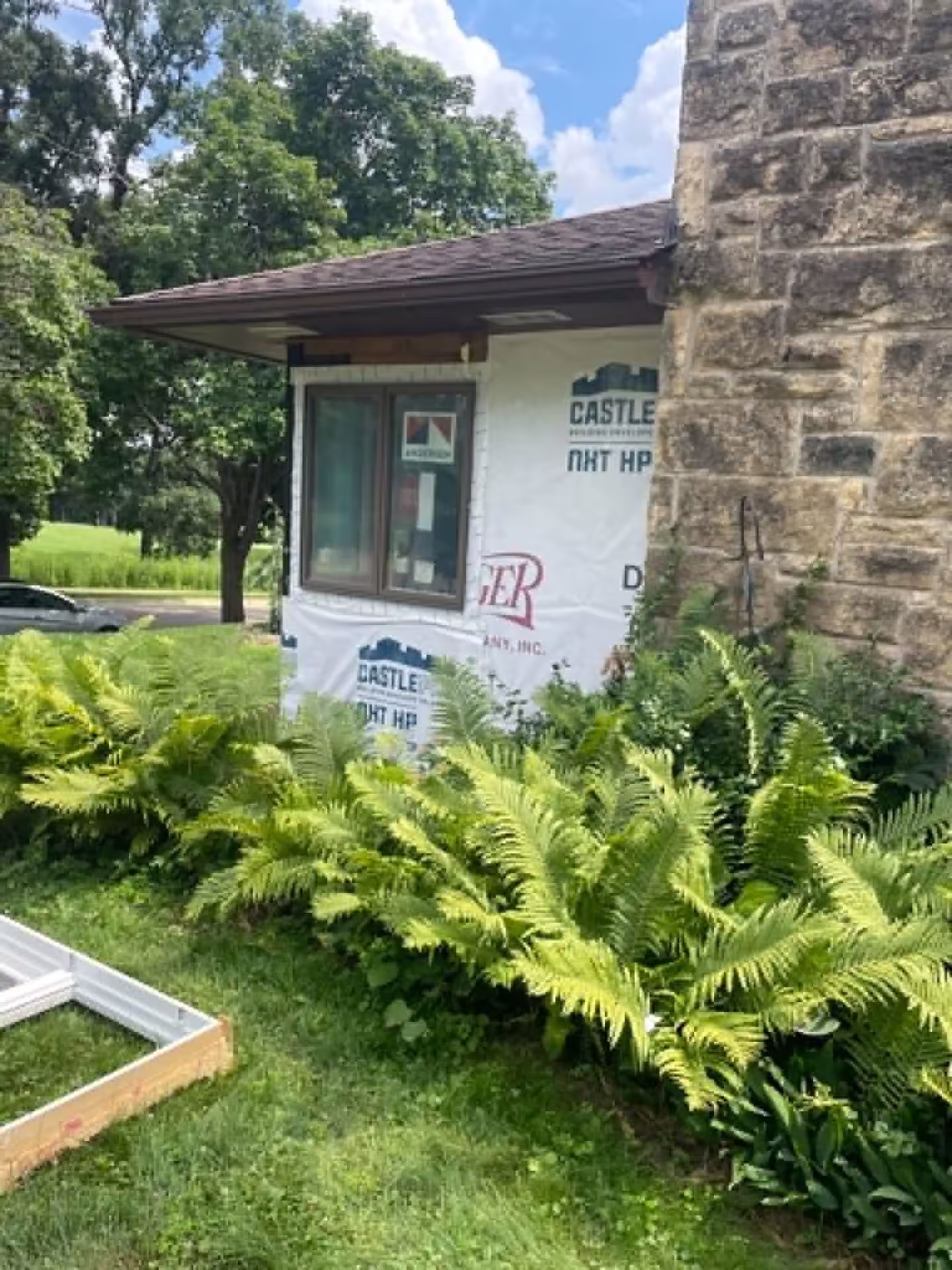 New Andersen window installed with Castle housewrap on a stone-accented home